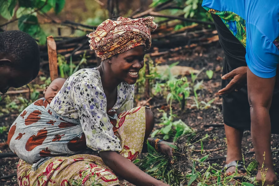 Une femme africaine souriante travaillant dans un champ, illustrant l'autonomisation et l'accompagnement au cœur de la mission SFEM à l'international.