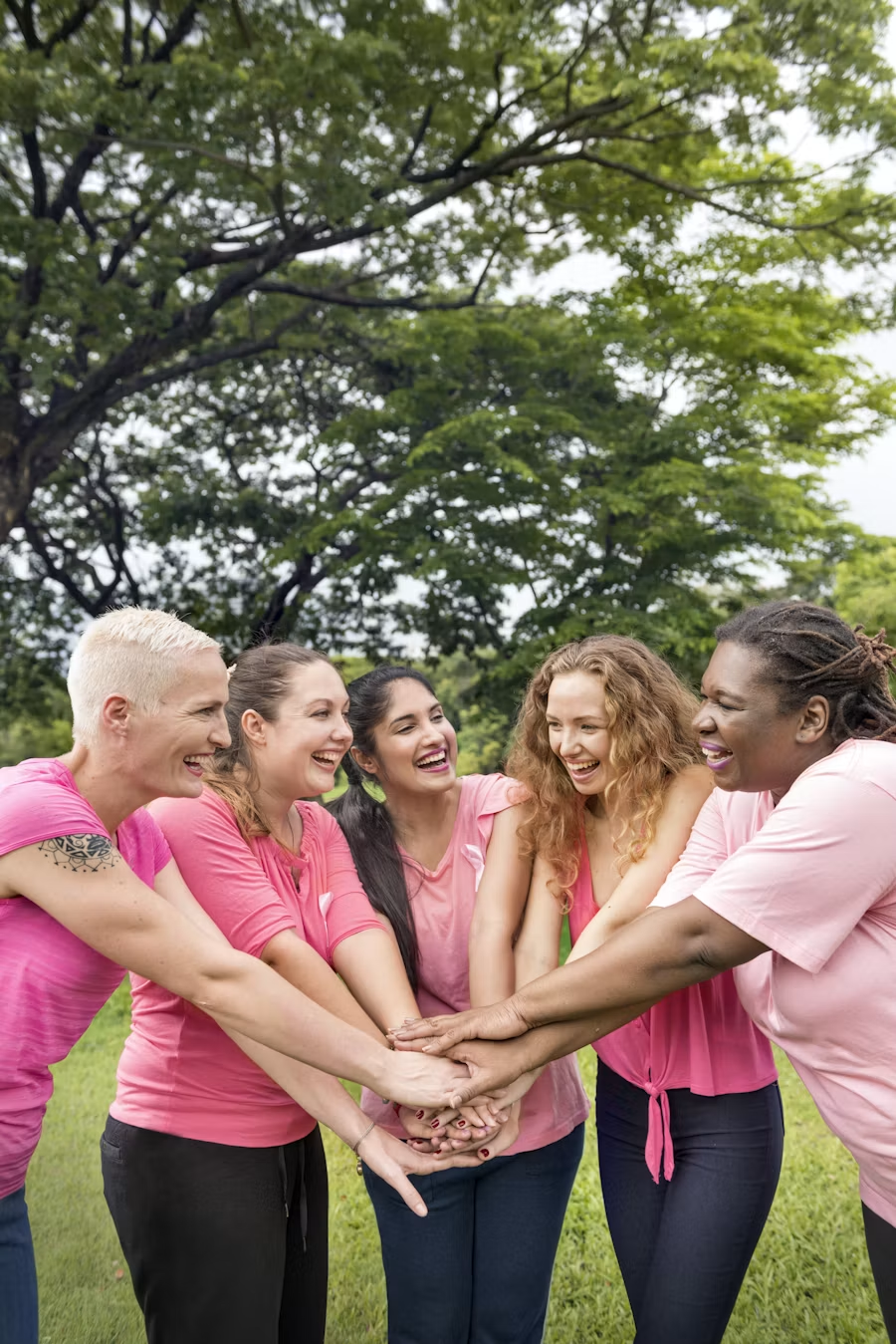Cinq femmes souriantes de diverses origines réunies ensemble en extérieur