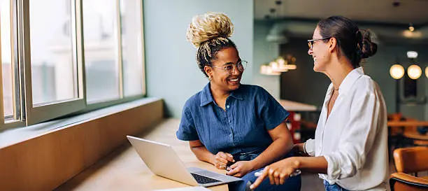 Deux femmes en discussion dans un espace de travail lumineux, illustrant le partenariat et l'accompagnement au cœur de la mission SFEM au Québec.
